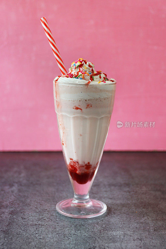 草莓奶昔/冰沙，红色和白色条纹的吸管，粉色的背景，注意前景